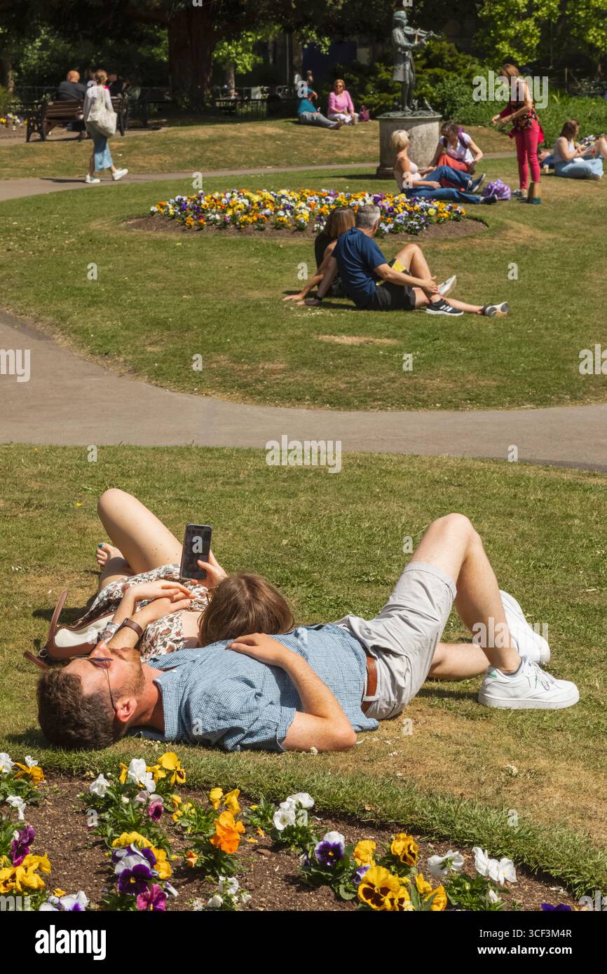 England, Somerset, Bath, Parade Gardens, Paare entspannen auf Grass Stockfoto
