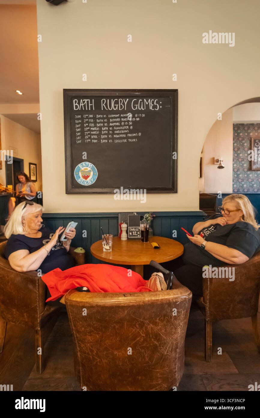 England, Somerset, Bath, The Huntsman Pub, zwei weibliche Kunden, die sich ein Mobiltelefon ansehen Stockfoto