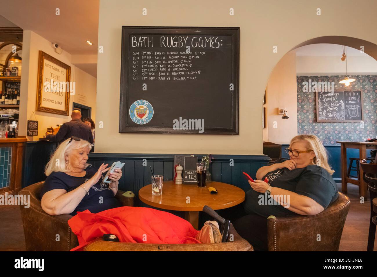 England, Somerset, Bath, The Huntsman Pub, zwei weibliche Kunden, die sich ein Mobiltelefon ansehen Stockfoto