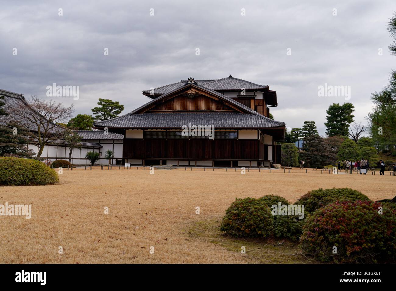 Traditionelle Holzstruktur des Schlosses Nijo in Kyoto, eingerahmt von Wintergärten und bewölktem Himmel Stockfoto