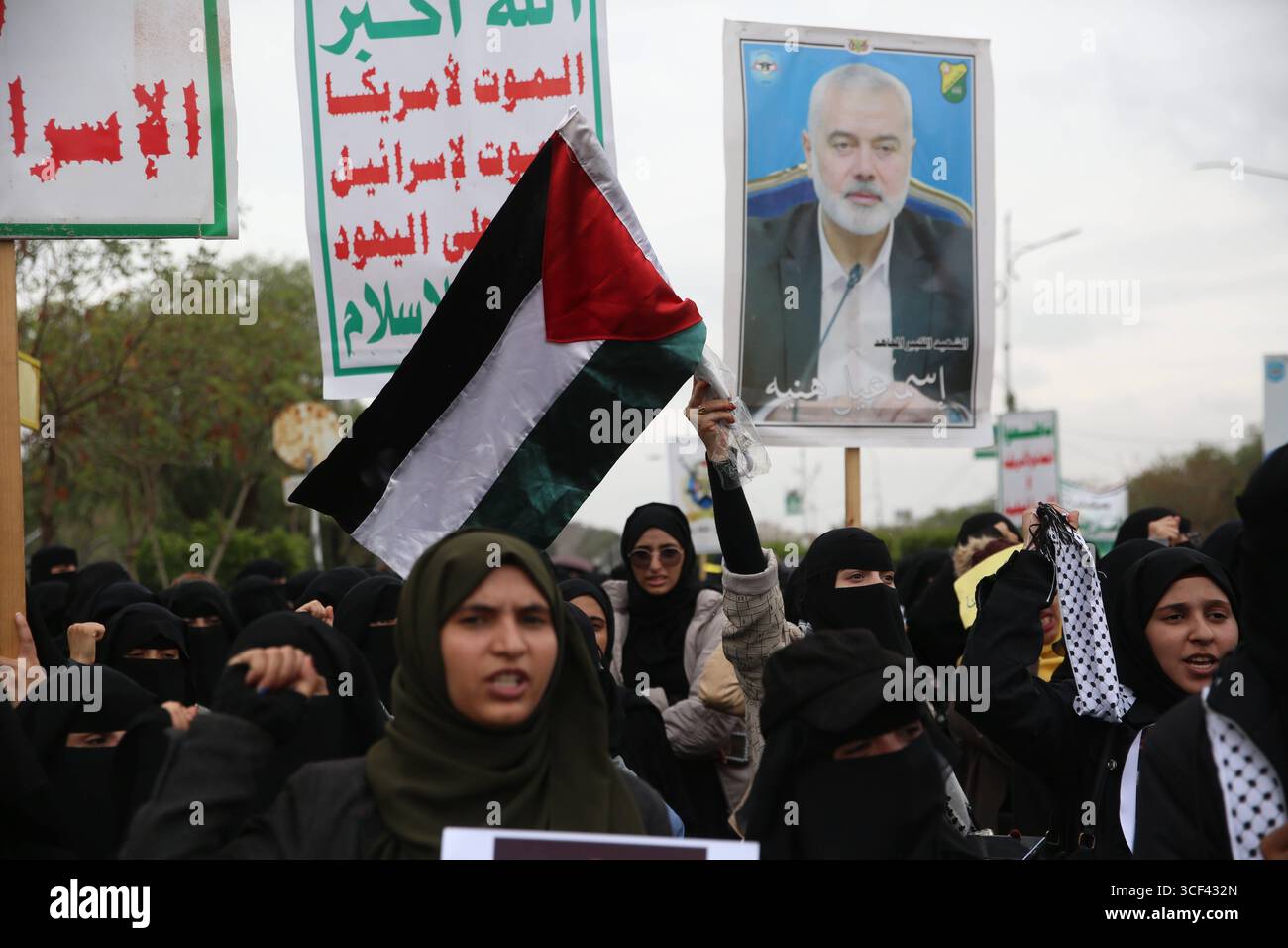 Solidaritätskundgebung für Gaza in Sana A - Ein Demonstrant schwingt eine palästinensische Flagge, während ein anderer ein Plakat hochhält, das den verstorbenen Hamas-Führer Ismail Haniyeh während einer Solidaritätskundgebung mit dem palästinensischen Volk am 20. August 2025 in Sana A, Jemen, zeigt. IMAGO/Sanaa Jemen Copyright: XHamzaxAlix Stockfoto