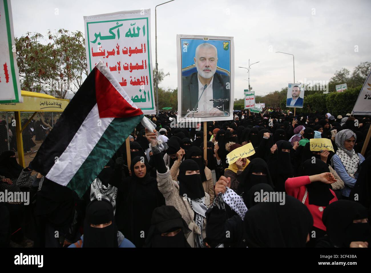 Solidaritätskundgebung für Gaza in Sana A - Ein Demonstrant schwingt eine palästinensische Flagge, während ein anderer ein Plakat hochhält, das den verstorbenen Hamas-Führer Ismail Haniyeh während einer Solidaritätskundgebung mit dem palästinensischen Volk am 20. August 2025 in Sana A, Jemen, zeigt. IMAGO/Sanaa Jemen Copyright: XHamzaxAlix Stockfoto