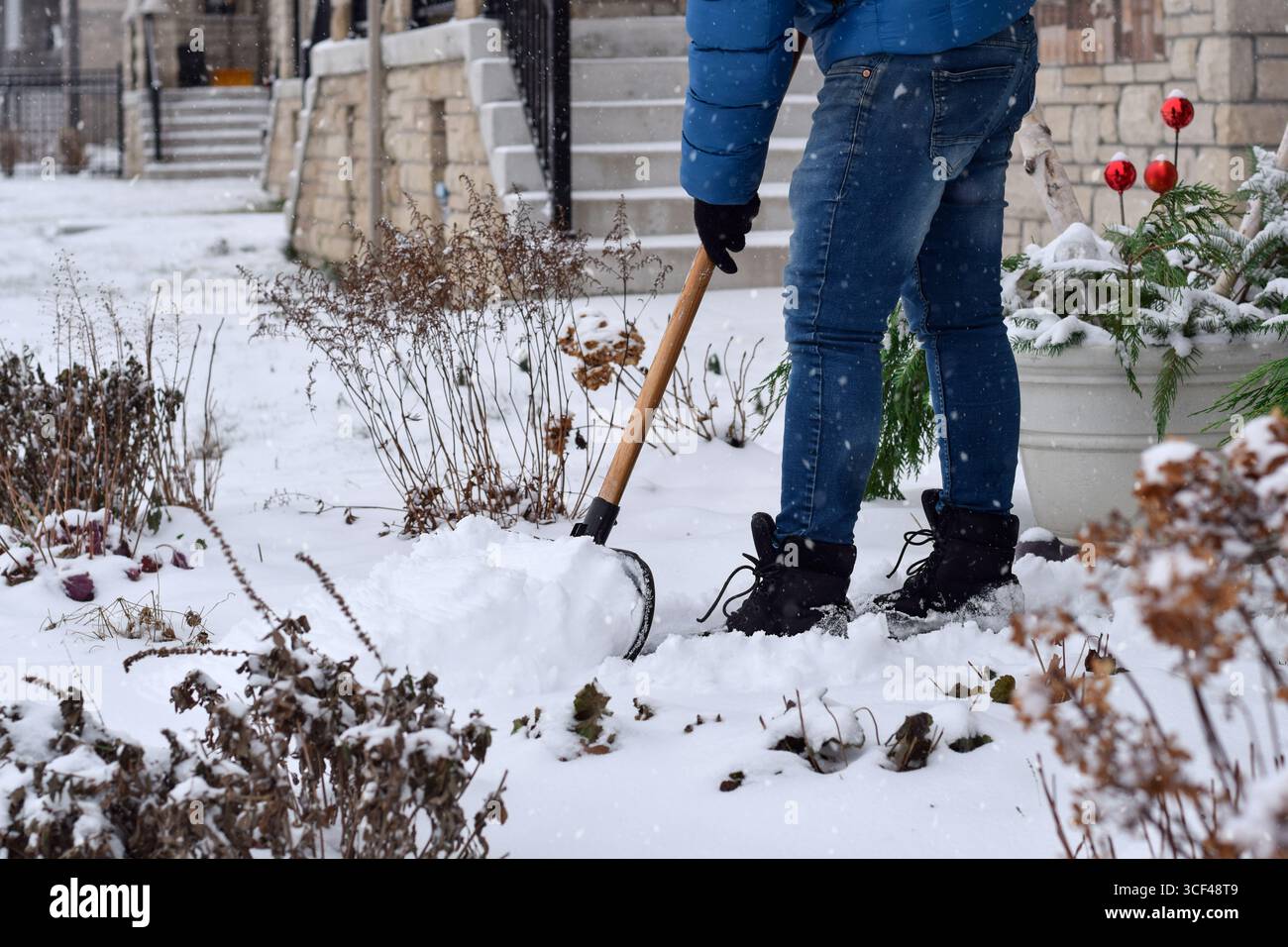 Mann schaufelt Schnee vom Vorhof eines Wohnhauses Stockfoto