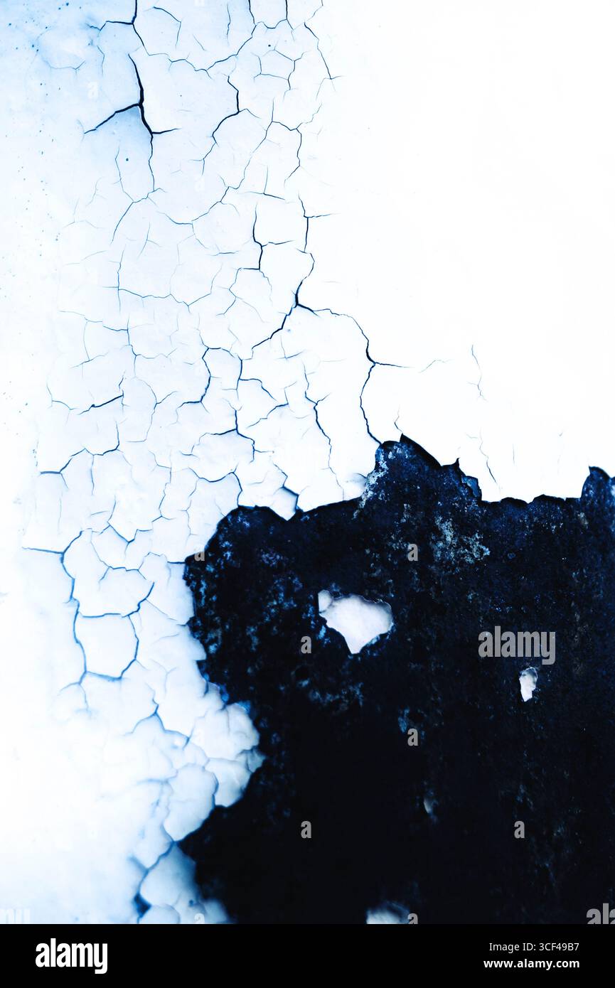 Weiße Farbe über einer schwarzen Metalloberfläche abblättert, Risse Stockfoto