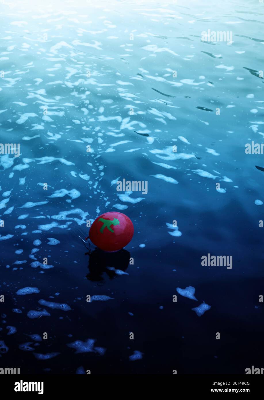 Ein roter Ballon mit einem grünen Ampelmann schwimmt auf dem blauen Wasser Stockfoto