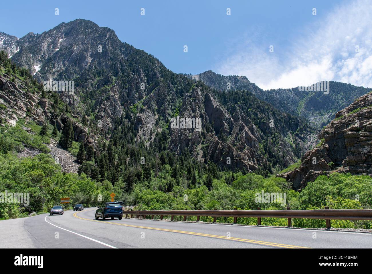 Straße mit Autos durch den Cottonwood Canyon auf Cottonwood Heights, Utah, USA, mit felsigen Bergen im Hintergrund vor blauem Himmel Stockfoto