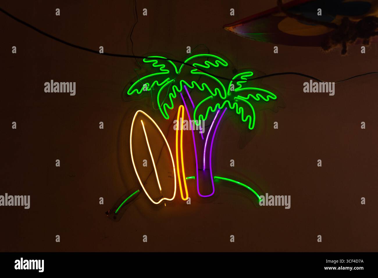Lebendiges Neonschild mit Palmen und Surfbrett, das an einen tropischen Strand erinnert. Perfekt, um jedem Innenraum einen Hauch von Farbe und Spaß zu verleihen Stockfoto