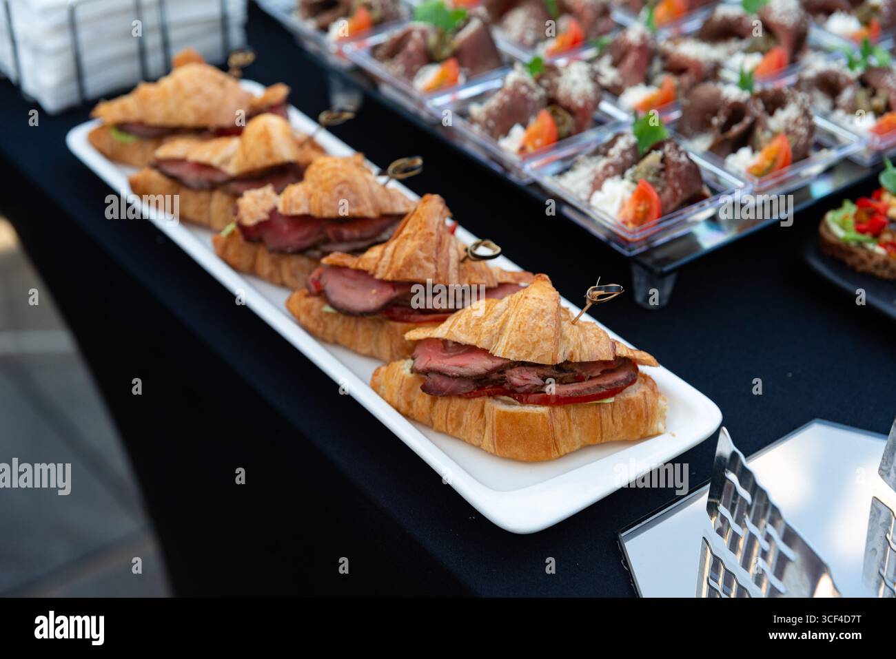 Elegant gestaltete Croissant-Sandwiches gefüllt mit Gourmet-Zutaten, auf einer Platte. Ideal für Catering-Veranstaltungen und kulinarische Präsentationen. Stockfoto