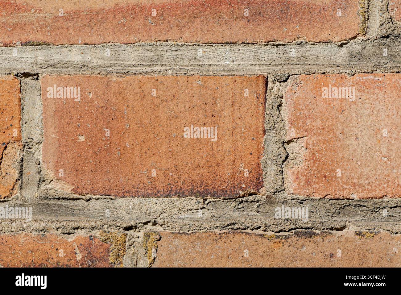 Eine intime Nahaufnahme einer alten Ziegelwand zeigt die feinen Details rauer Oberflächen, zersplitterter Mörtel und subtile Farbvariationen. Stockfoto