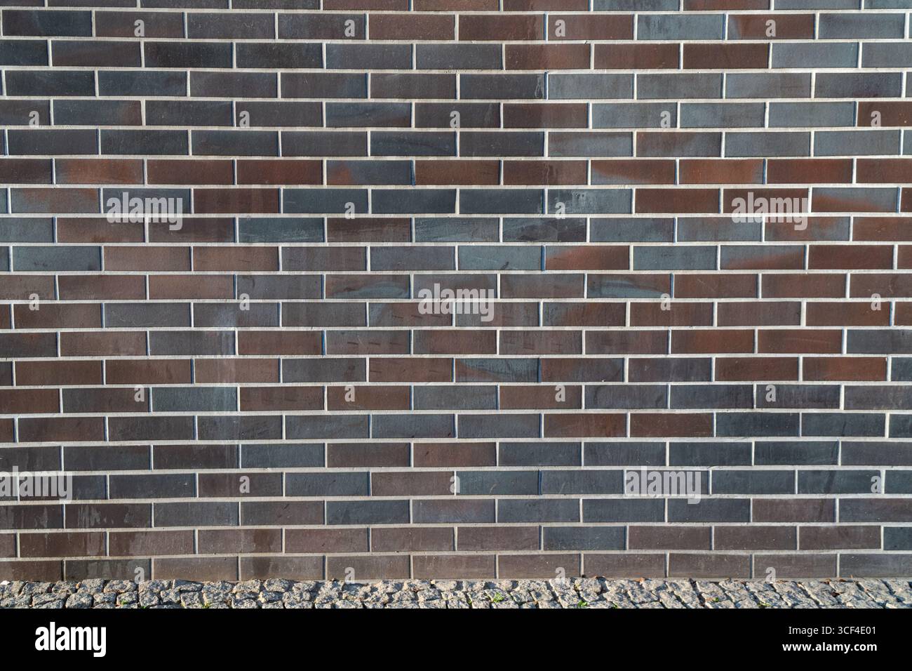 Ein klares Vollformatbild einer dunklen, modernen Ziegelwand mit geometrischer Präzision und minimalem Design. Stockfoto