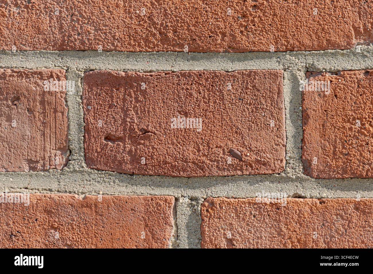 Alte rote Ziegelwand mit Unvollkommenheiten, Poren und verwitterten Texturen. Die unebenen Oberflächen erzählen eine ruhige Geschichte von Zeit und Ausdauer. Stockfoto