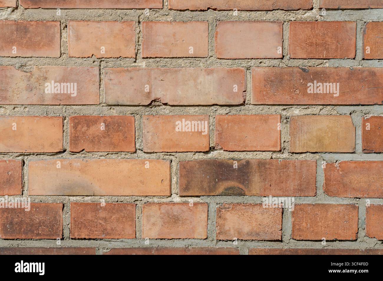 Eine Nahaufnahme einer alten Ziegelmauer mit unregelmäßigen Mustern, verwitterten Oberflächen, Verfärbungen, Makel und rauen Texturen. Stockfoto