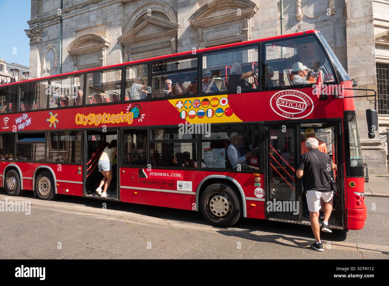 Leute, die bei sonnigem Wetter einen Doppeldeckerbus mit offenem Oberdeck sehen. Kopenhagen, Dänemark - 19. August 2025. Stockfoto
