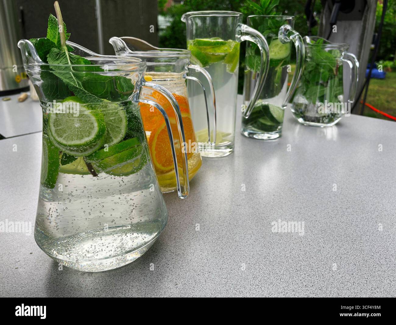 Fruchtige Erfrischungsgetränke stehen in einer Reihe auf einem Gartentisch. Stockfoto