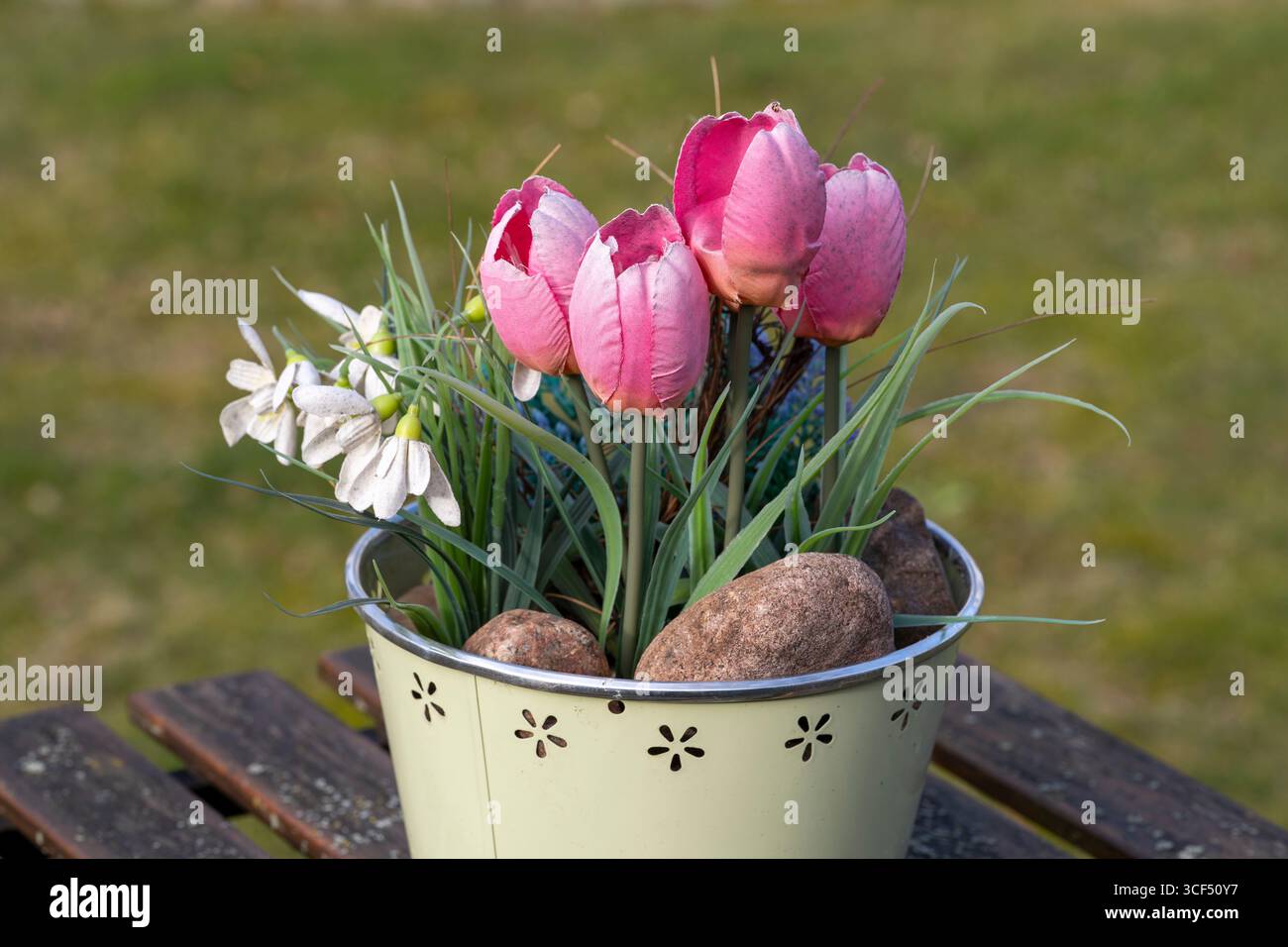 Künstliche Tulpen und Schneeglöckchen in einem Blumentopf auf einem verwitterten Holztisch, Dekoration Stockfoto