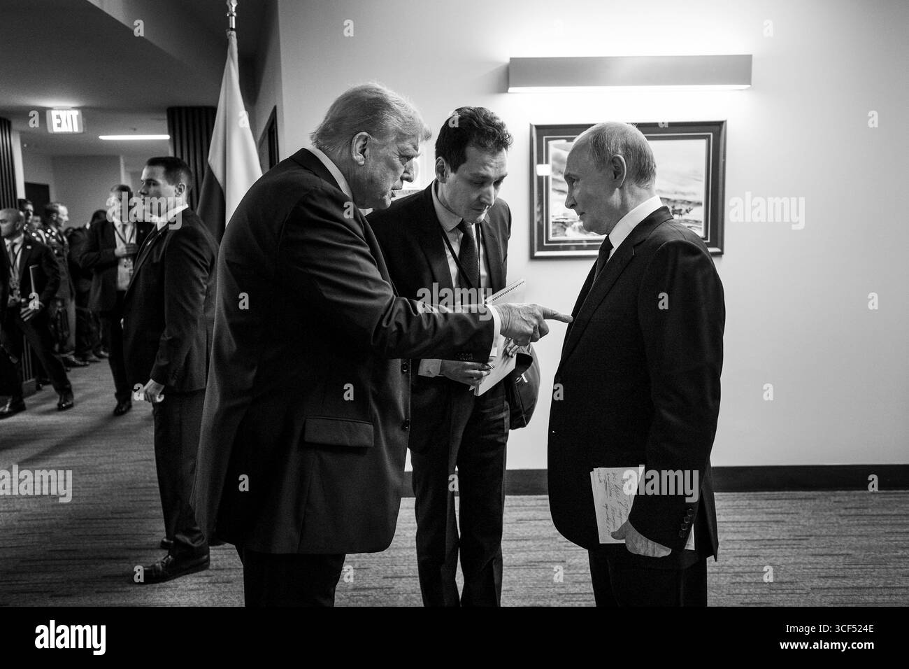 Anchorage, Vereinigte Staaten von Amerika. August 2025. US-Präsident Donald Trump, links, und russischer Präsident Wladimir Putin, rechts, sprechen hinter der Bühne durch einen nicht identifizierten Dolmetscher, Center, bevor sie an einer gemeinsamen Pressemitteilung auf der Joint Base Elmendorf Richardson, 15. August, in Anchorage, Alaska, teilnehmen. Trump lädt Putin zu Gesprächen ein, um den russischen Krieg in der Ukraine zu beenden. Quelle: Daniel Torok/White House Photo/Alamy Live News Stockfoto