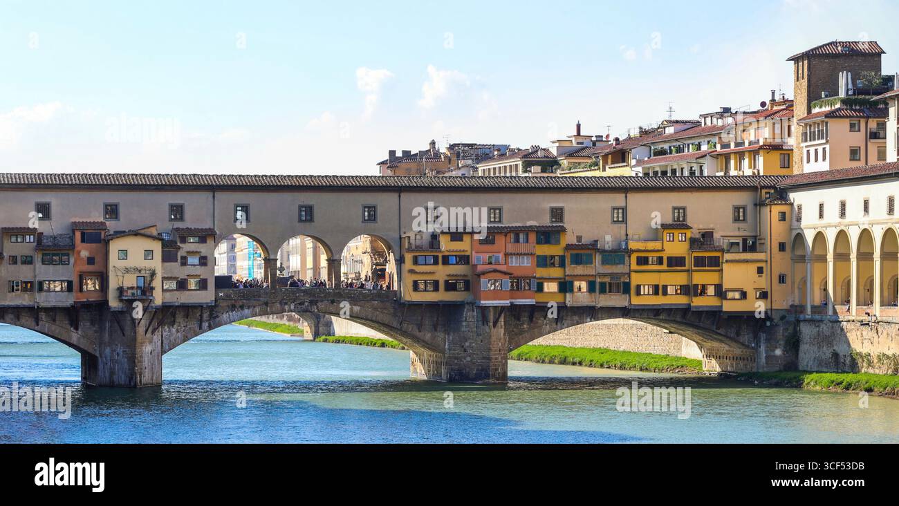 Ponte Vecchio, eine historische überdachte Brücke in Florenz, Italien, zeigt ihre einzigartige Architektur mit Geschäften entlang der Brücke, die eine malerische Szene über dem Fluss Arno unter klarem Himmel schaffen Stockfoto
