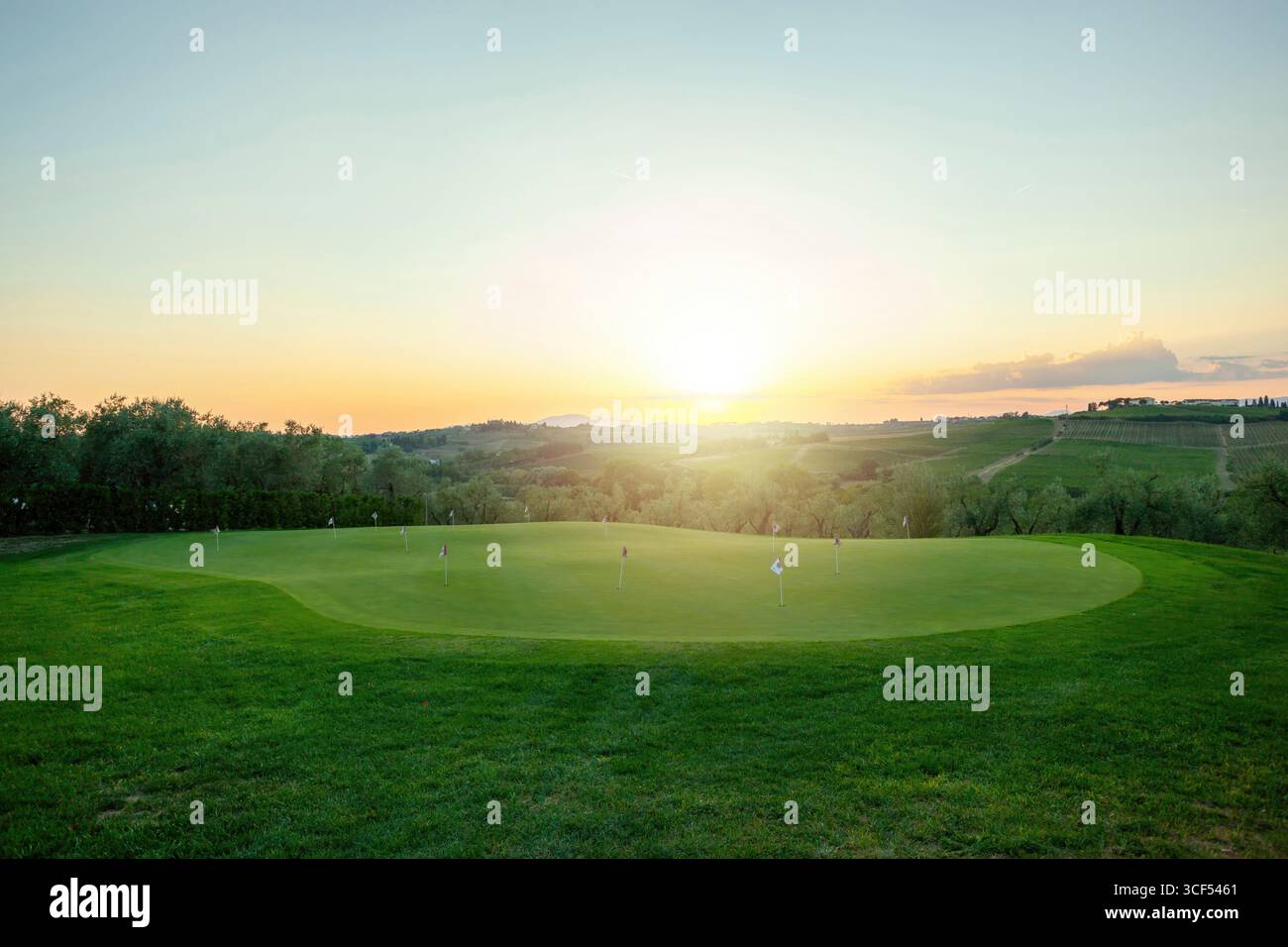 Der Golfplatz ist in goldenes Licht getaucht, während die Sonne über den sanften Hügeln und Weinbergen der toskanischen Landschaft untergeht Stockfoto