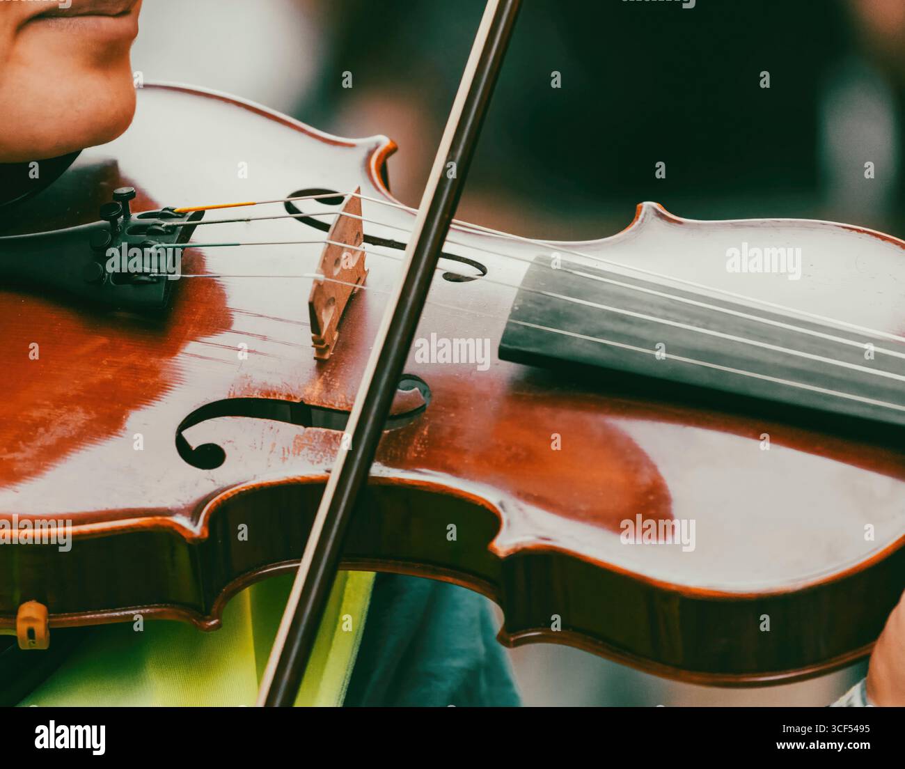 Nahaufnahme eines Musikers, der während einer Live-Vorstellung leidenschaftlich Geige spielt und die komplizierten Details des Instruments und die anmutige Bewegung des Bogens erfasst Stockfoto
