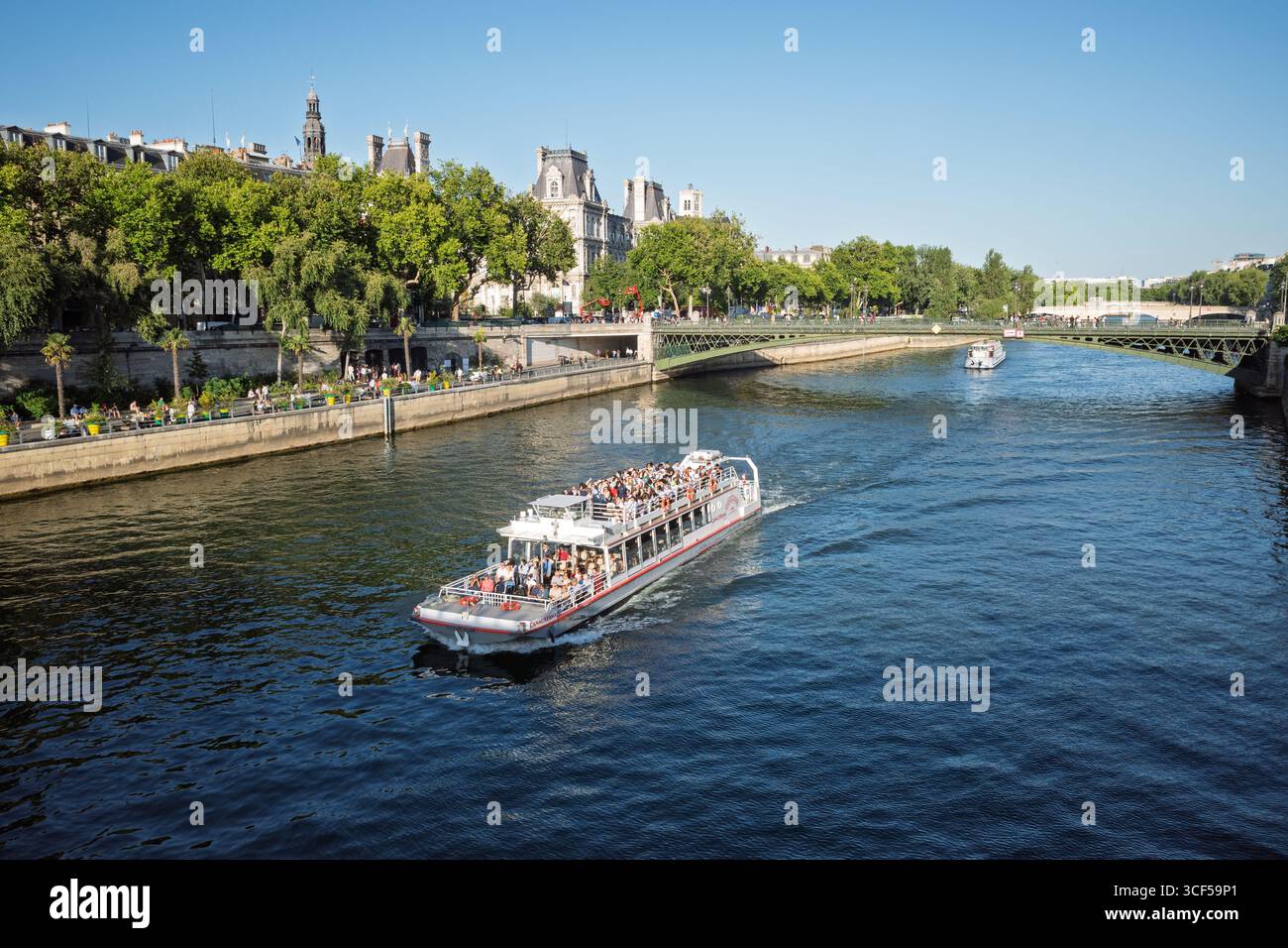 Ein belebtes Ausflugsboot fährt auf der seine in Paris mit historischen Gebäuden entlang der Ufer. Stockfoto