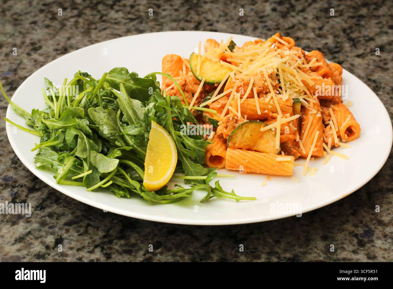Nahaufnahme eines zubereiteten Rigatoni-Nudelgerichts mit Zucchini und Rucola Stockfoto
