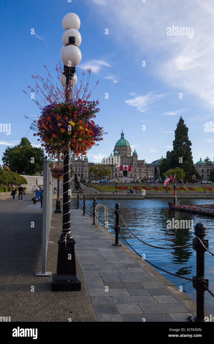 Victoria Inner Harbour in British Columbia - ikonische Parlamentsgebäude in British Columbia mit grüner Kuppel, kanadischen Flaggen und Blumenlaternen auf der alle Stockfoto