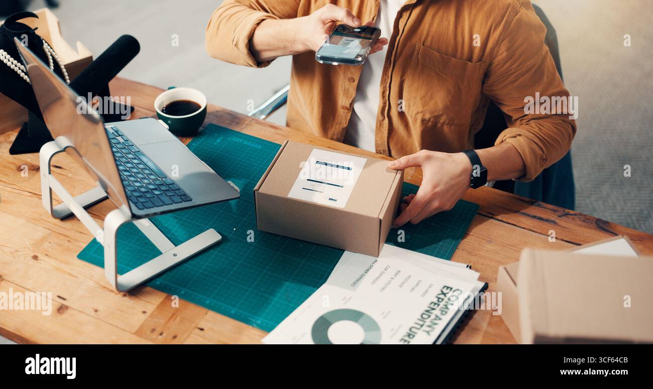 Box, Hände und Telefon mit Person im Logistikbüro zum Scannen von Barcodes oder zur Paketverfolgung. Inventar, Foto und Lieferkette mit einem Mann am Schreibtisch Stockfoto