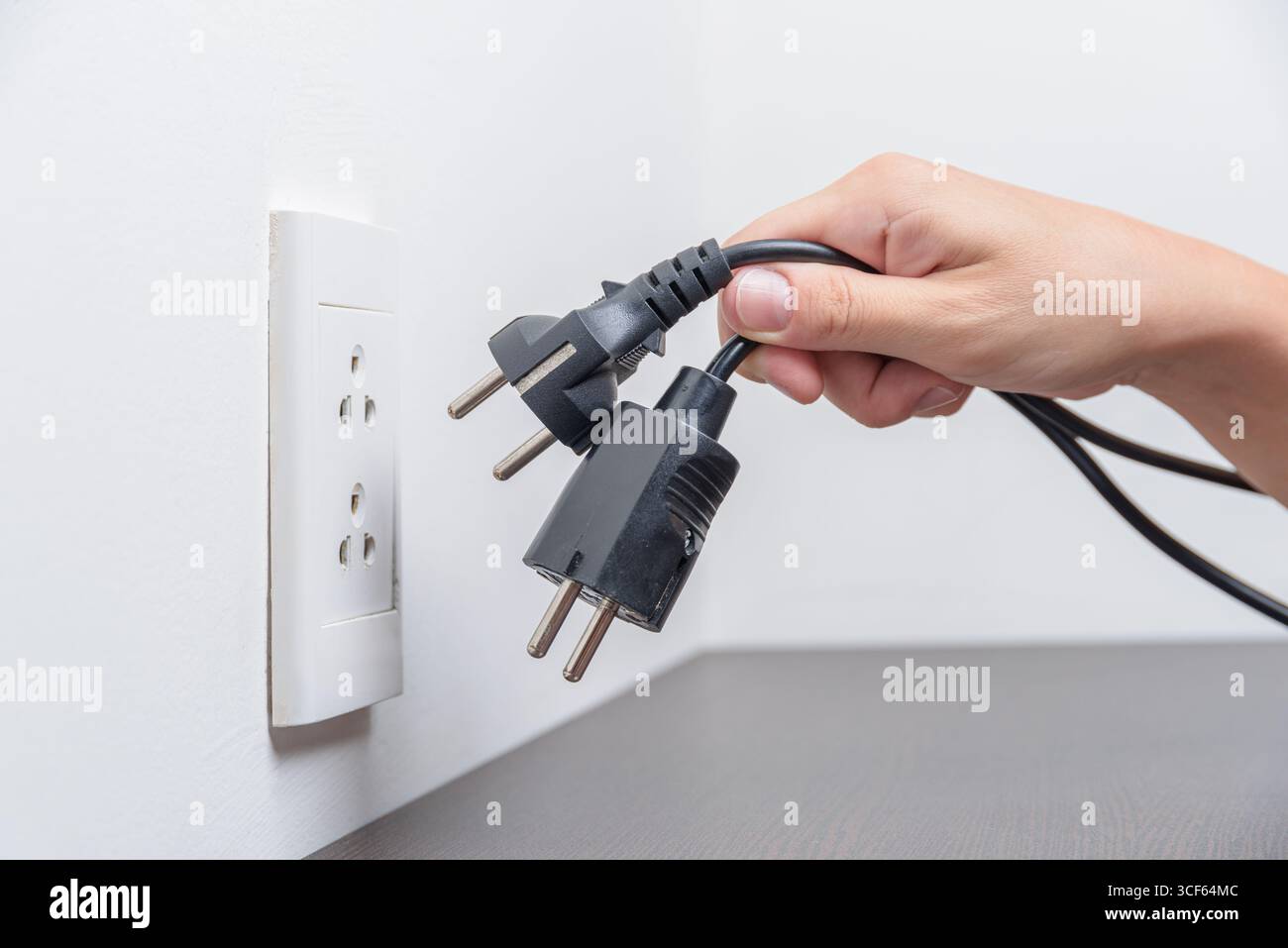 Stecken Sie elektrische Stecker von Hand in die Steckdose. Elektrische Überlastung Stockfoto