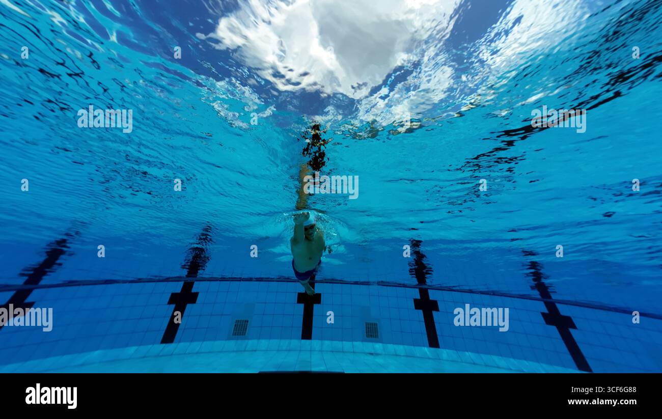 Unterwasserblick eines männlichen Schwimmers, der in einem klaren blauen Swimmingpool trainiert Stockfoto