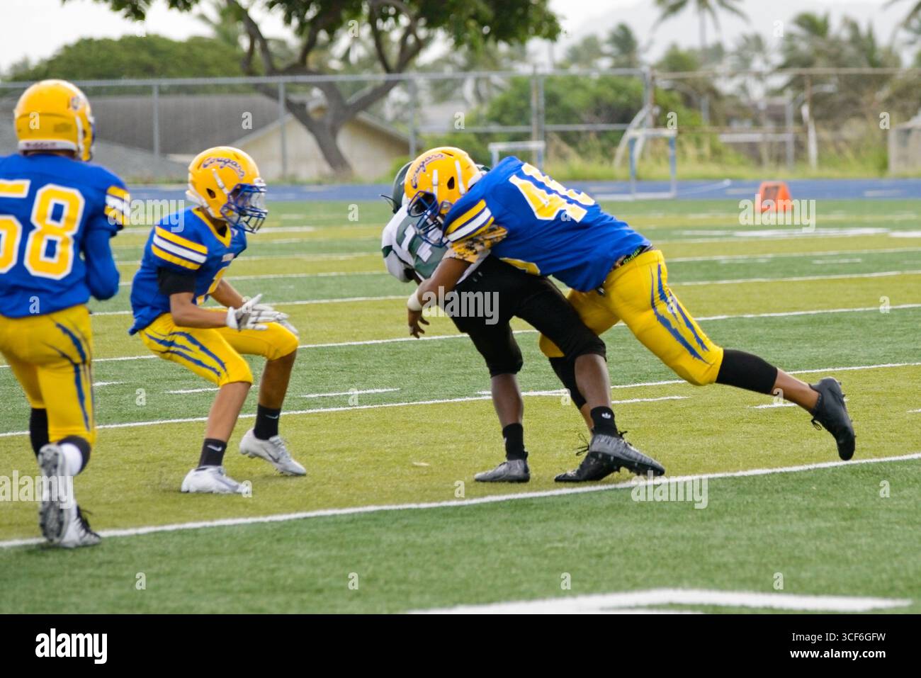 Die High School, die zurück läuft, kämpft um jeden Hof, als ein wilder Verteidiger versucht, ihn auf dem Weg in die Endzone zu stürzen. Stockfoto