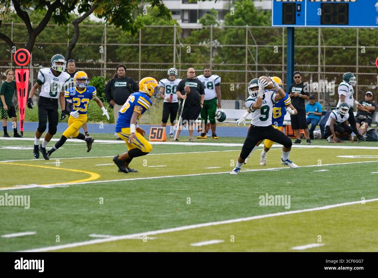 Die High School, die zurück läuft, kämpft um jeden Hof, als ein wilder Verteidiger versucht, ihn auf dem Weg in die Endzone zu stürzen. Stockfoto