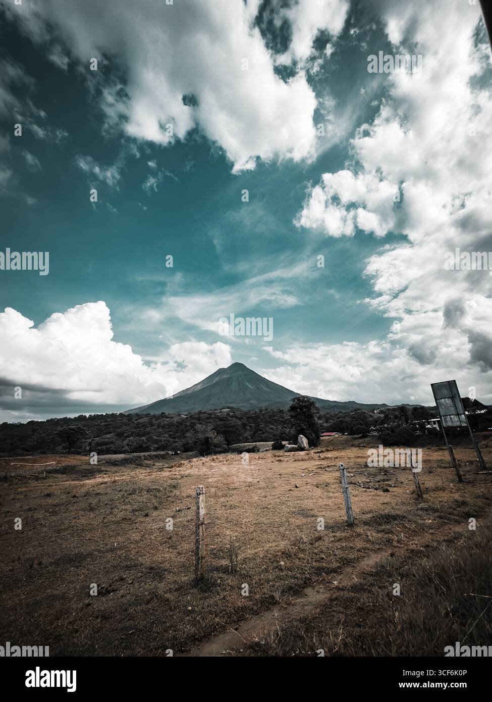 Panoramablick auf den Vulkan Arenal in Costa Rica mit bewölktem Himmel und ländlicher Landschaft - Smartphone-aufgenommenes Stockfoto