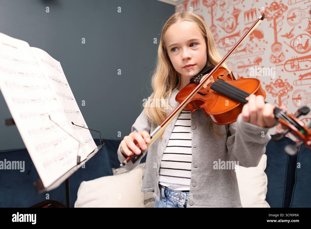 Mädchen, das zu Hause Geige spielt, mit Musik auf dem Notenständer Stockfoto