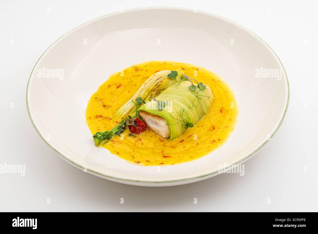 Mit Zucchini umwickeltes Fischfilet in Safran-angereicherter Gelbsoße Stockfoto
