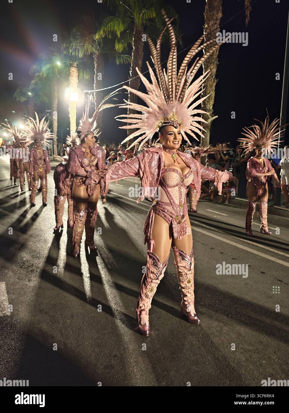 Aguilas, Murcia, Spanien. August 2025. Überschwängliche Tänzerin in Ballkleid und Federn im Haar bei der Sommerparade des Aguilas-Karnevals Stockfoto