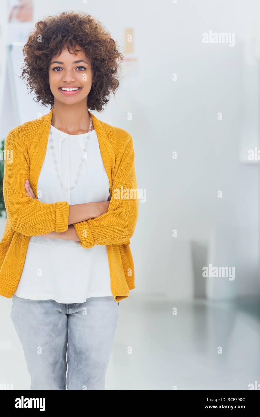 Afroamerikanerin, die Arme im Büro gekreuzt in Strickjacke und Halskette, Kopierraum Stockfoto