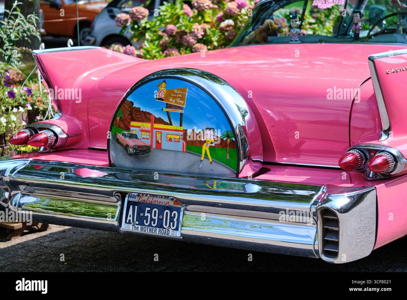 Ruinerwold, Niederlande; 17. August 2024: Rückseite des rosa Cadillac mit legendären Heckflossen, Chromleuchten und lackierter Betty Boop-Reserveradabdeckung während Stockfoto