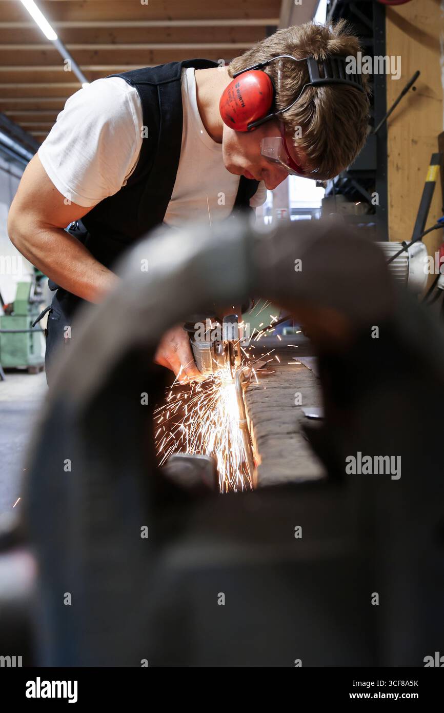 Hamburg, Deutschland. August 2025. David Geisinger, Schmiedelehrling, arbeitet mit einem Winkelschleifer in der Werkstatt von Schmiede Lehmann in Hamburg-Altona. Quelle: Christian Charisius/dpa/Alamy Live News Stockfoto