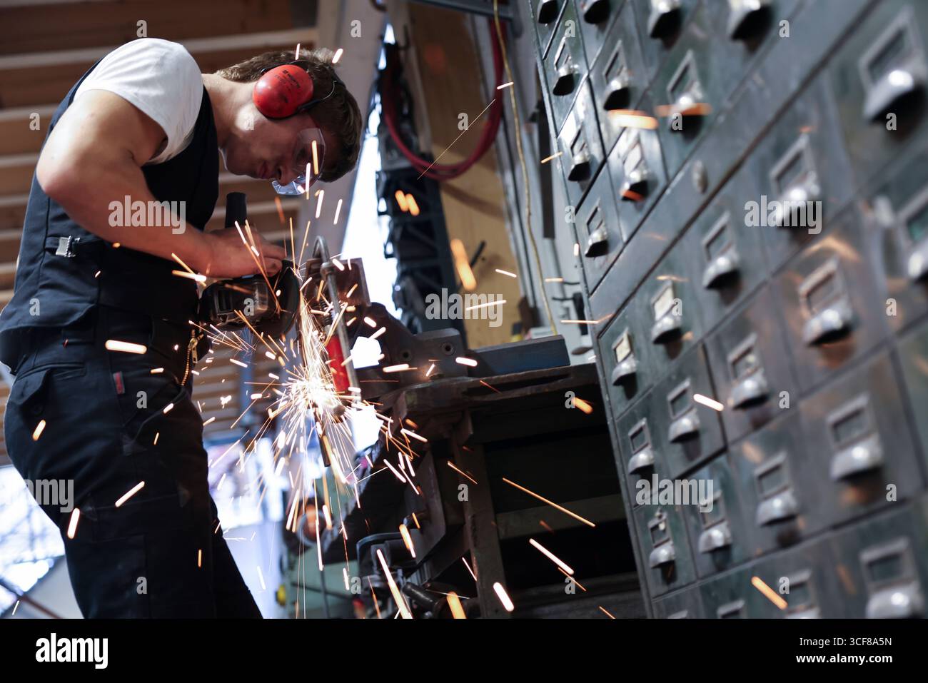 Hamburg, Deutschland. August 2025. David Geisinger, Schmiedelehrling, arbeitet mit einem Winkelschleifer in der Werkstatt von Schmiede Lehmann in Hamburg-Altona. Quelle: Christian Charisius/dpa/Alamy Live News Stockfoto