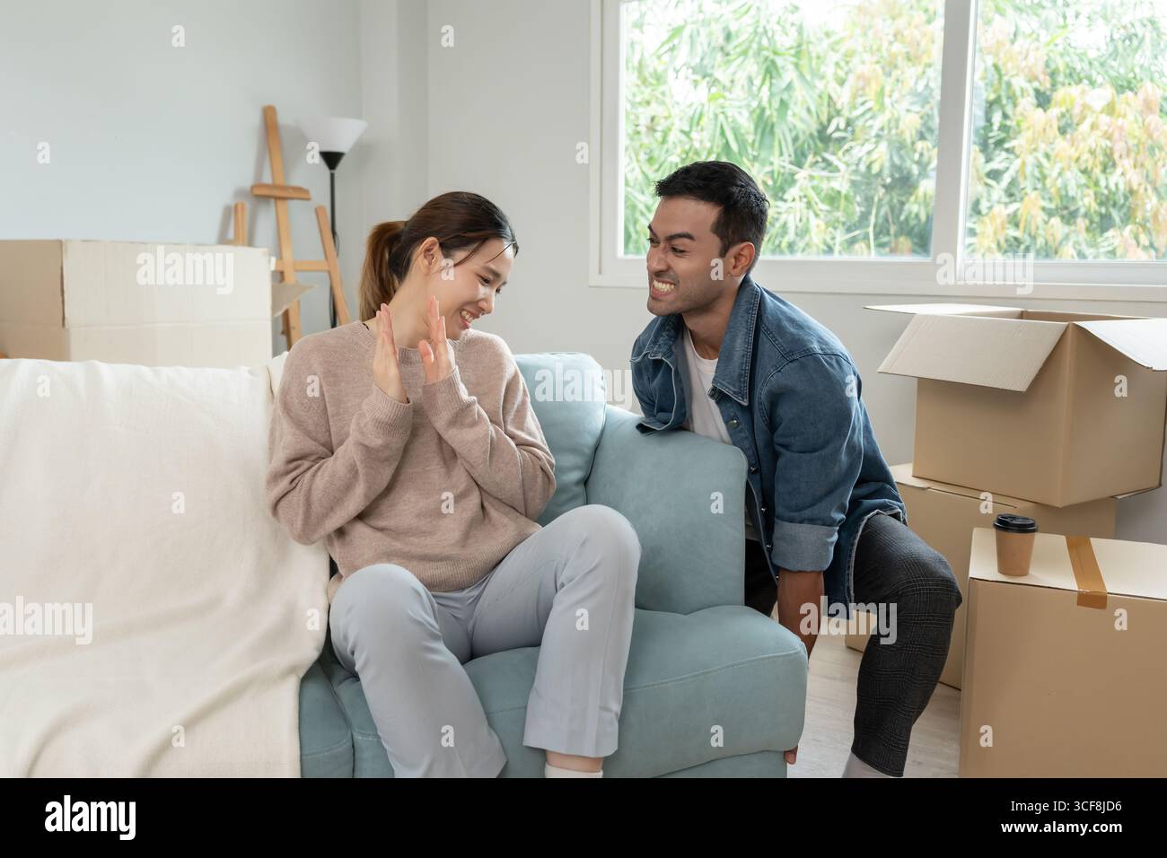 Umzug, Umzug. Die Frau fühlt sich gut und neckt ihren Mann, im Zimmer war eine Pappschachtel mit persönlichen Sachen und Möbeln Stockfoto