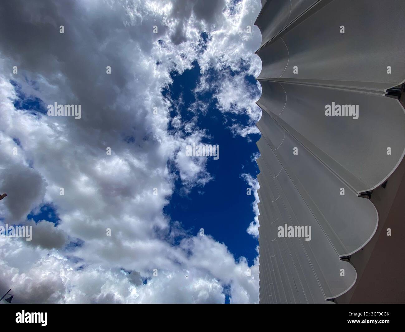 Geometrische, moderne Gebäudefassade, die sich in Pescara, Italien, nach oben erhebt und ein architektonisches Muster vor wolkenblauem Hintergrund enthüllt Stockfoto