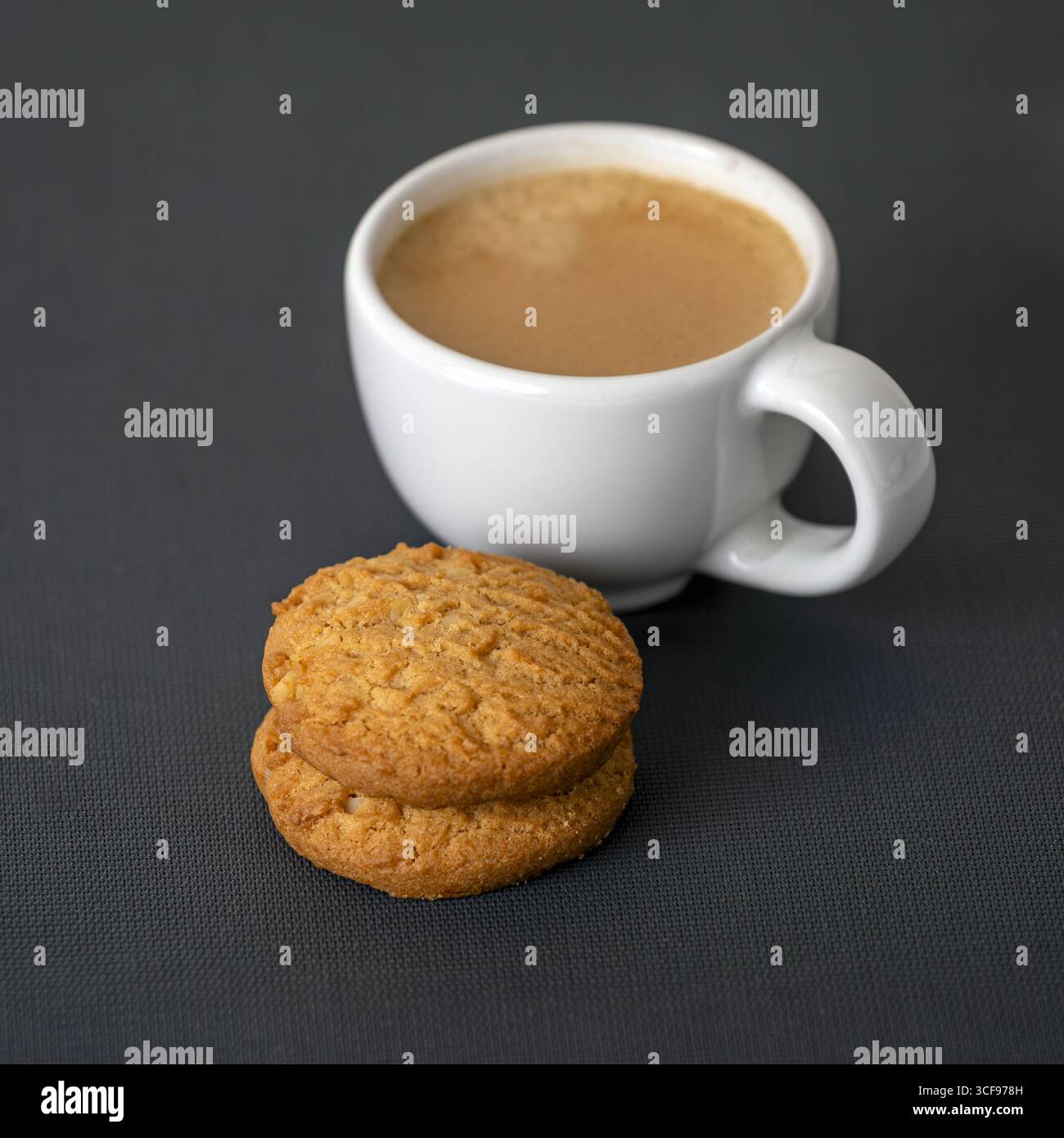Ein Espresso-Shot-Kaffee mit cremigem Schaum und zwei Haferkeksen auf dunklem Tisch, gemütliche und einladende Snackszene, perfekt für eine entspannende Pause oder einen morgendlichen Genuss Stockfoto