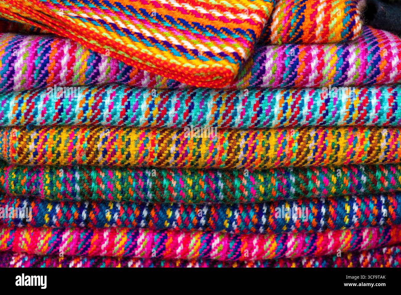 Traditionelle handgefertigte ecuadorianische Textilien und Stoffe, Otavalo Markt, Ecuador. Konzentrieren Sie sich auf den Stapel von Textilien. Stockfoto