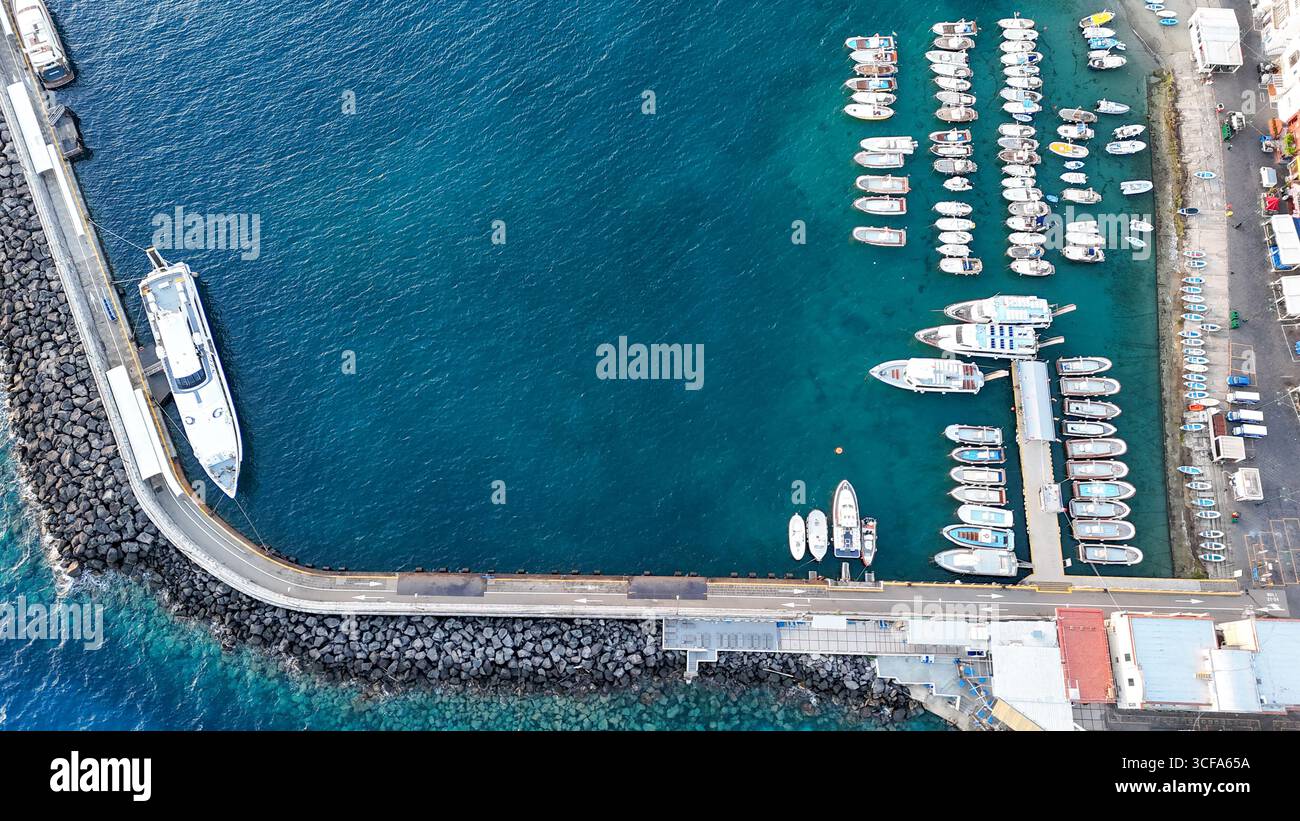 Farbenfrohe Boote legten an einem lebhaften Yachthafen unter klarem blauen Himmel in einer Küstenstadt an Stockfoto