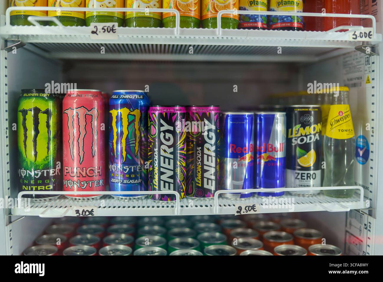 Cremona, Italien 25. Juli 2025 Dosen und Flaschen Monster Energy. Red Bull Zitronennatron. Und Schweppes tonica ordentlich in Regalen in einem Kühlschrank angeordnet Stockfoto