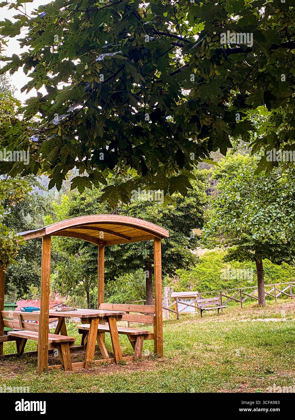 Ein hölzerner Picknickunterstand bietet Schatten im Rocca Pia Park in den Abruzzen und bietet einen komfortablen Ruheplatz inmitten einer grünen Landschaft Stockfoto