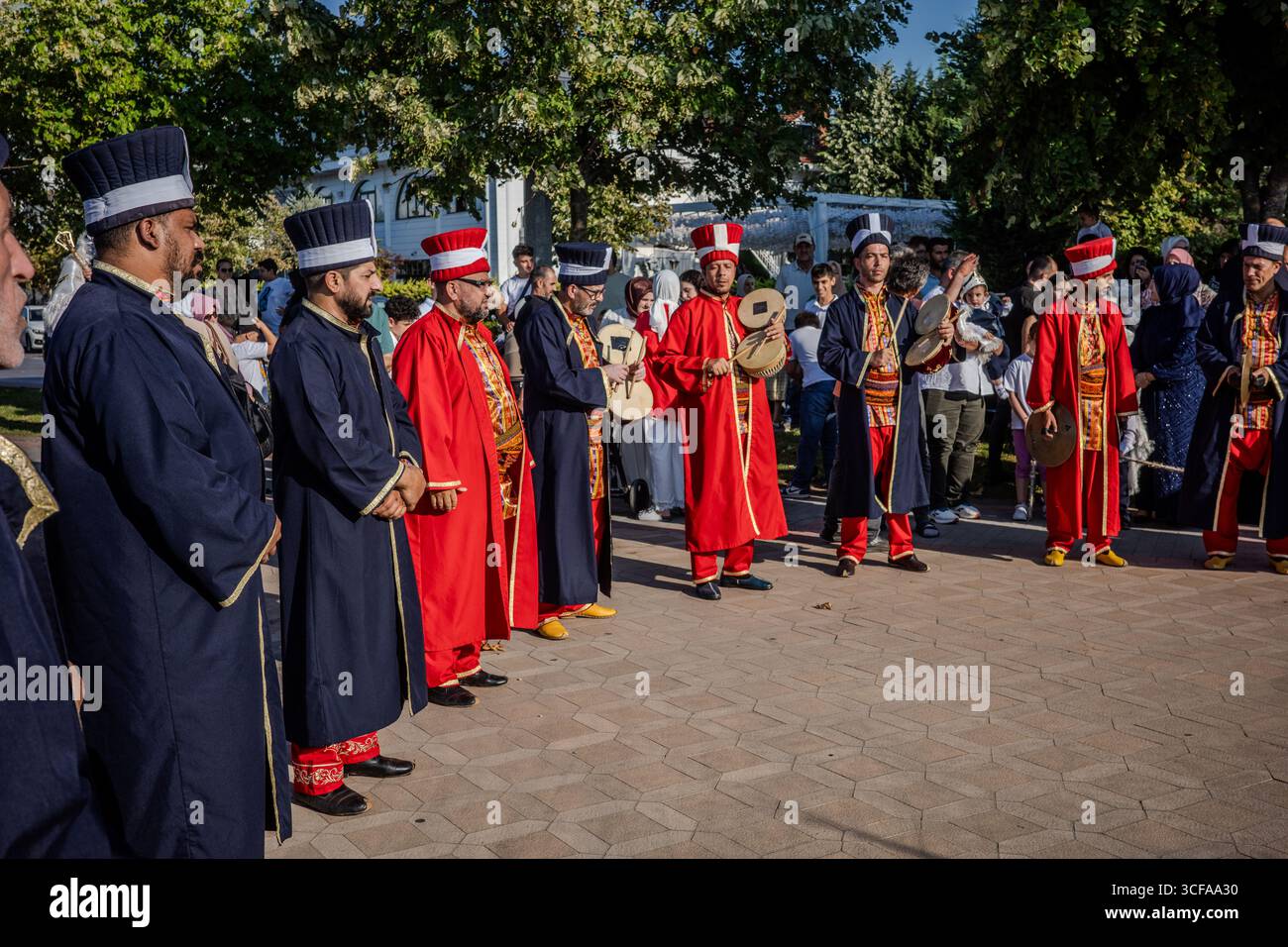 Die Mitglieder der osmanischen Mehter-Band in bunten traditionellen Kostümen treten mit Trommeln und Zimbeln in Başiskele, Kocaeli, Türkei auf, während die Zuschauer die Außenwelt beobachten Stockfoto