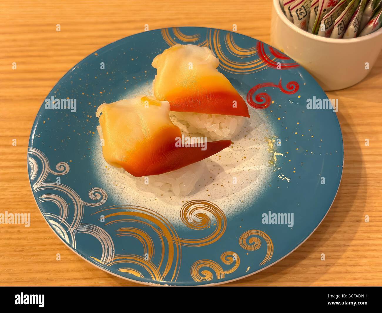 Nahaufnahme von zwei Hokkigai- oder Surf-Muschel-Sushi auf einer blau-goldenen Platte. Ein gängiges Produkt in Sushi-Restaurants mit Förderband in Japan. Stockfoto