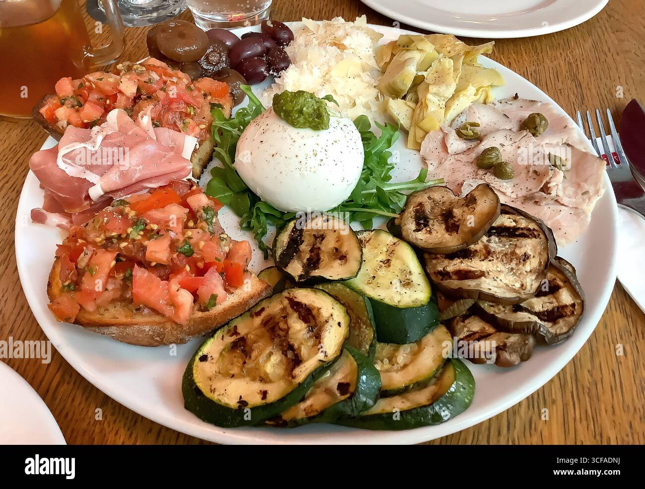 Rustikale italienische Antipastoplatte mit verschiedenen Burrata, Bruschetta, Schinken und gegrilltem Gemüse. Stockfoto