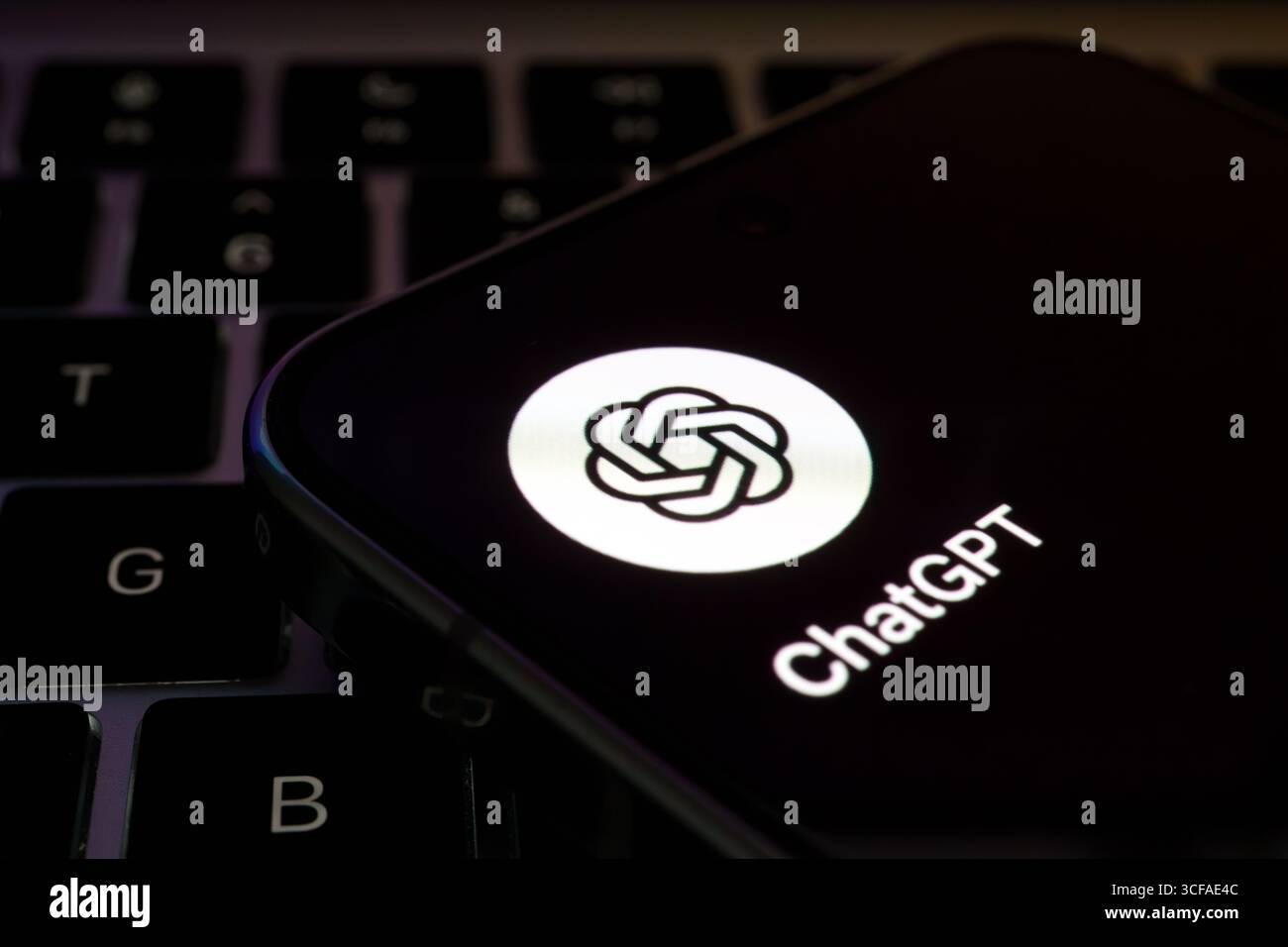 Das Symbol der ChatGPT-App leuchtet auf dem Smartphone auf der Tastatur des Laptops auf. Stafford, Vereinigtes Königreich, 21. August 2025 Stockfoto